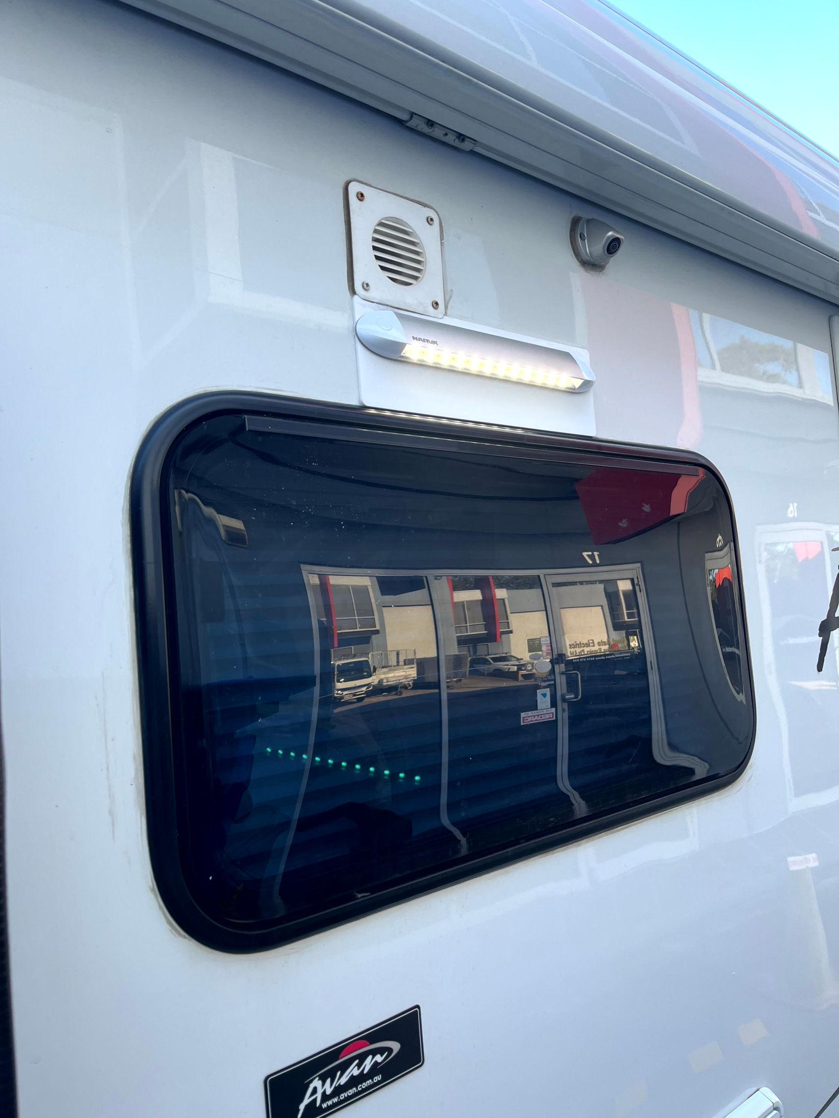 White RV side with window, vent, and LED light.