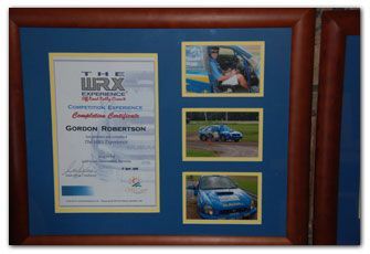 Framed certificate and photos of a rally car experience, including a blue Subaru.