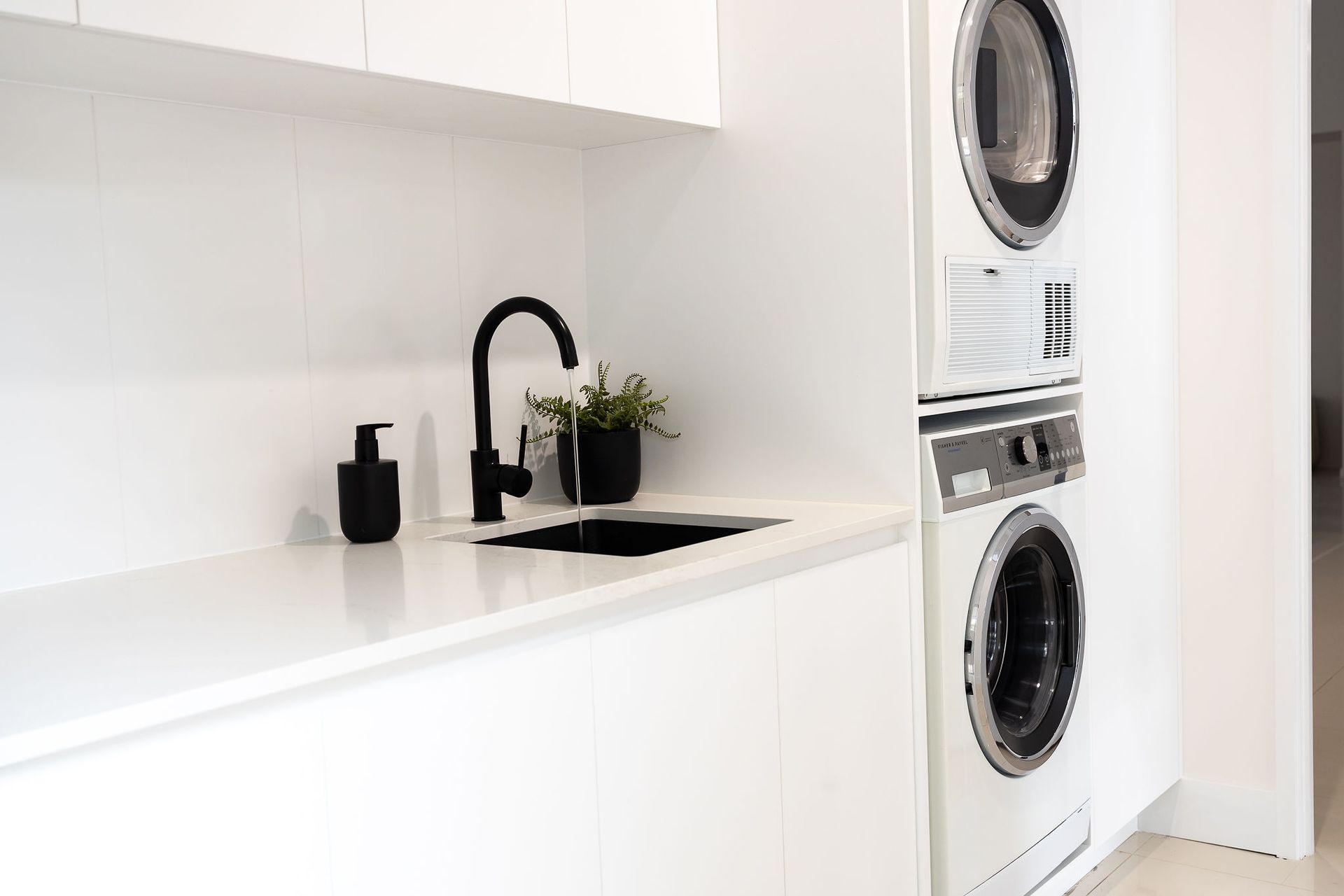 White Laundry Room With Black Faucet, Sink, and Stacked Washer— Truline Cabinets In Tuchekoi, QLD