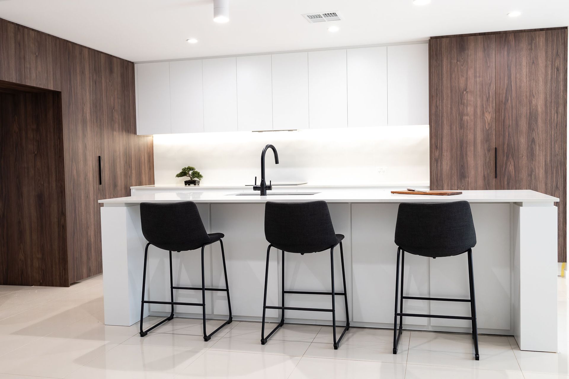 Modern Kitchen With White Island, Black Bar Stools, and Wood Paneling — Truline Cabinets In Tuchekoi, QLD