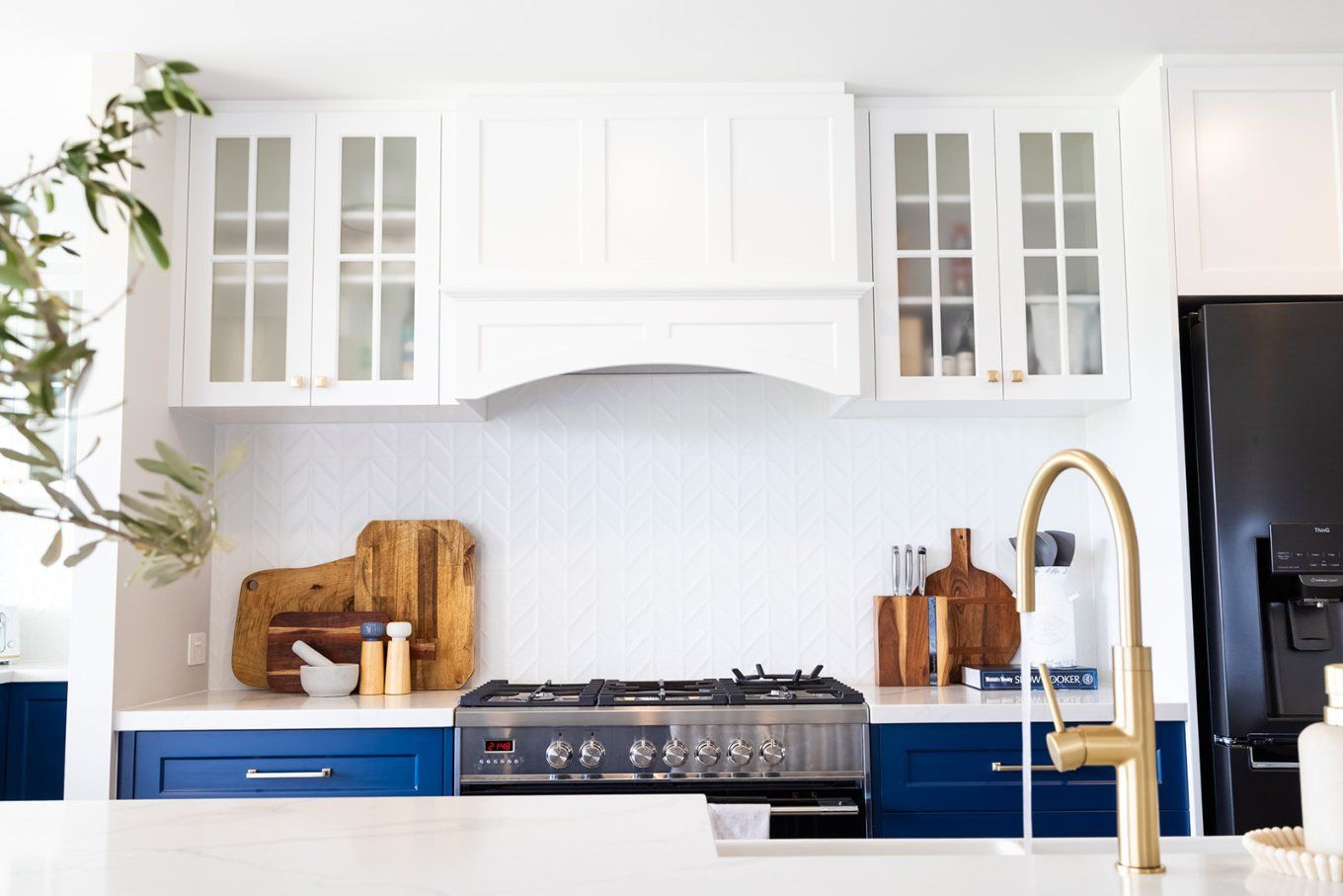 Kitchen With White Cabinets, Navy Blue Lower Cabinets, a Gas Range, Gold Faucet, and Wooden Cutting Boards — Truline Cabinets In Tuchekoi, QLD
