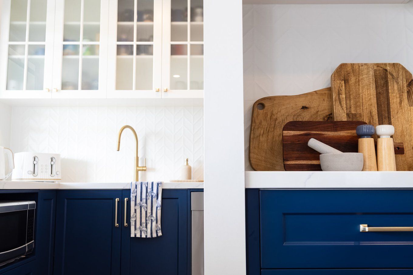Blue and White Kitchen Featuring Upper Glass-front Cabinets, Brass Faucet, and Wooden Cutting Boards — Truline Cabinets In Tuchekoi, QLD
