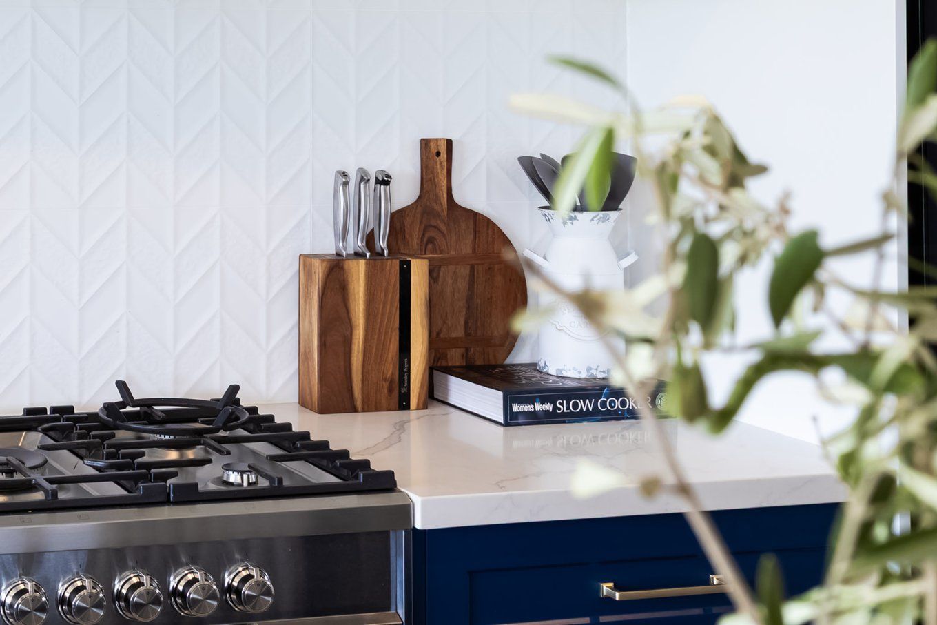 A Kitchen Counter With a Wooden Knife Block, Cutting Board, and a Stove — Truline Cabinets In Tuchekoi, QLD