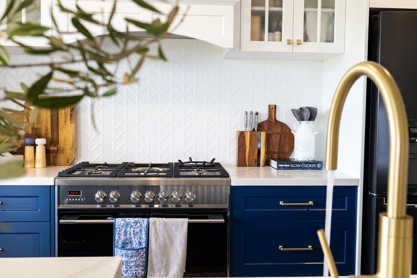 A Modern Kitchen With Navy Blue Cabinets, White Countertops, a Stainless Steel Stove, and a Gold Faucet — Truline Cabinets In Tuchekoi, QLD