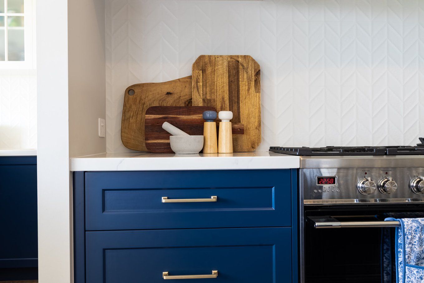 Blue Kitchen Cabinets With Silver Handles and a White Countertop, Topped With Wooden Cutting Boards and Salt and Pepper Shakers — Truline Cabinets In Tuchekoi, QLD