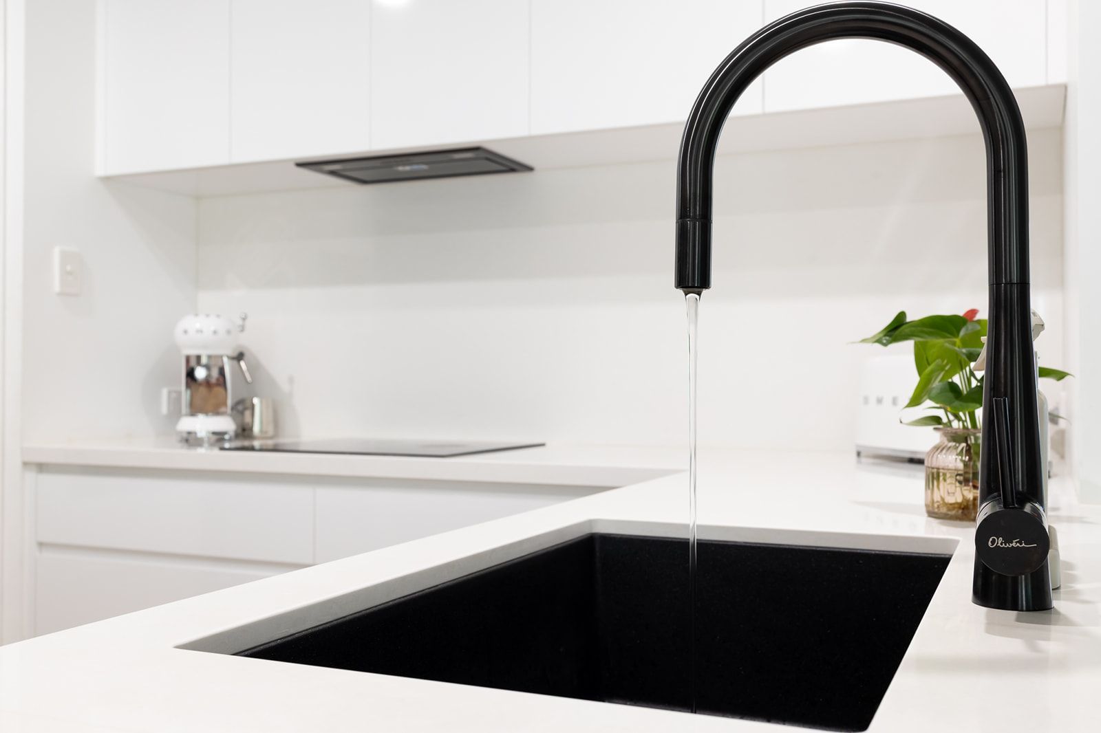 Black Kitchen Faucet With Water Flowing Into a Black Sink — Truline Cabinets In Tuchekoi, QLD