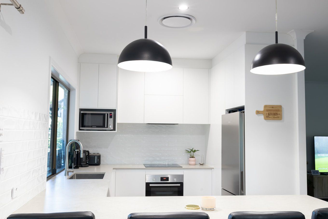 Modern White Kitchen With Black Pendant Lights, a Stainless Steel Refrigerator, and a Microwave — Truline Cabinets In Tuchekoi, QLD