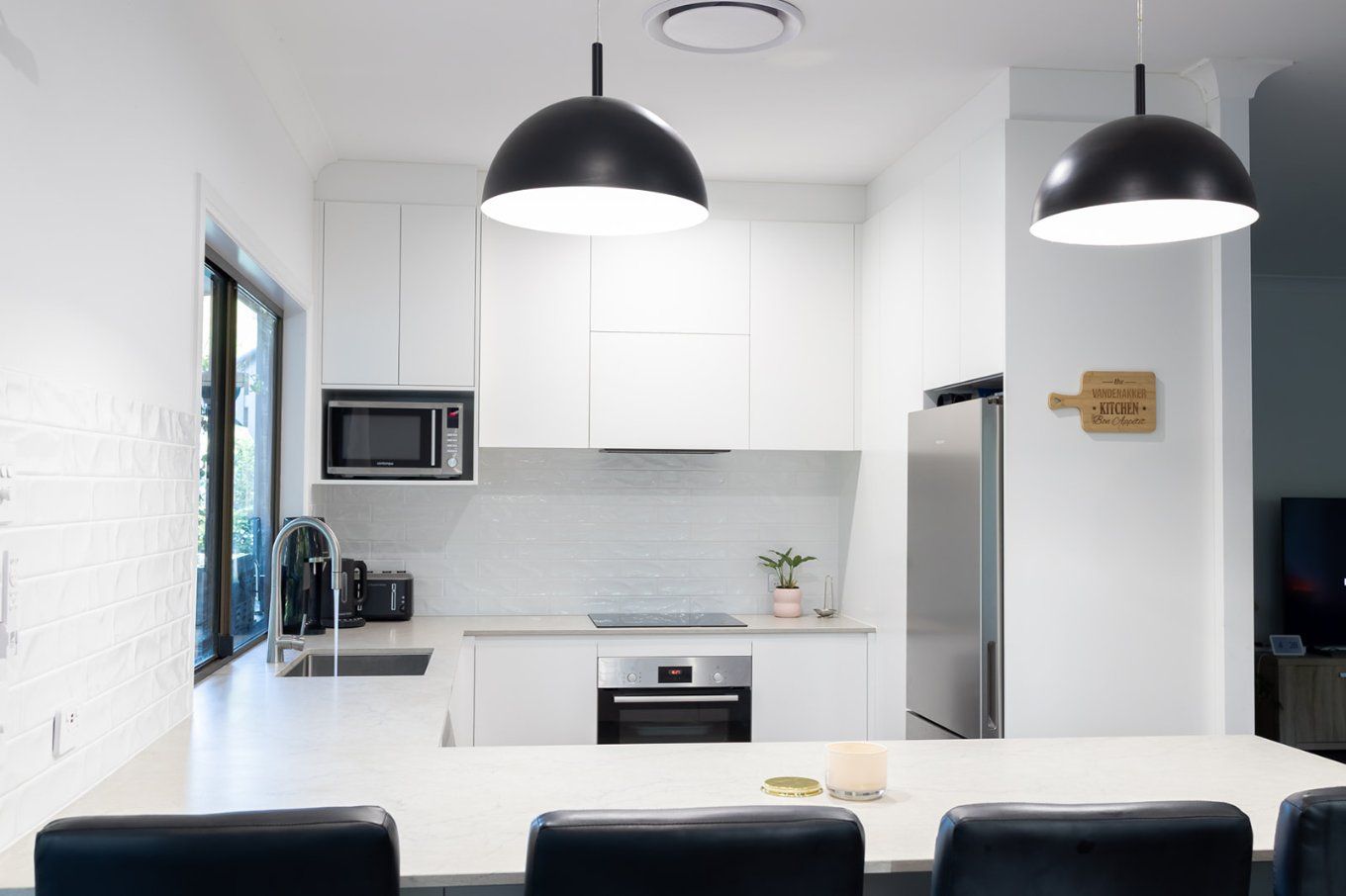 A Modern White Kitchen With a Breakfast Bar and Stainless Steel Appliances — Truline Cabinets In Tuchekoi, QLD