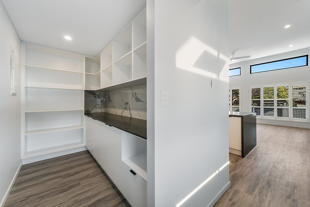 Pantry With White Shelves, Counter, and a Hallway With a Kitchen Island and Windows — Truline Cabinets In Tuchekoi, QLD