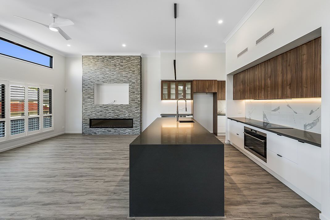 Modern Kitchen With a Dark Island, White Countertops, and a Stone Fireplace — Truline Cabinets In Tuchekoi, QLD