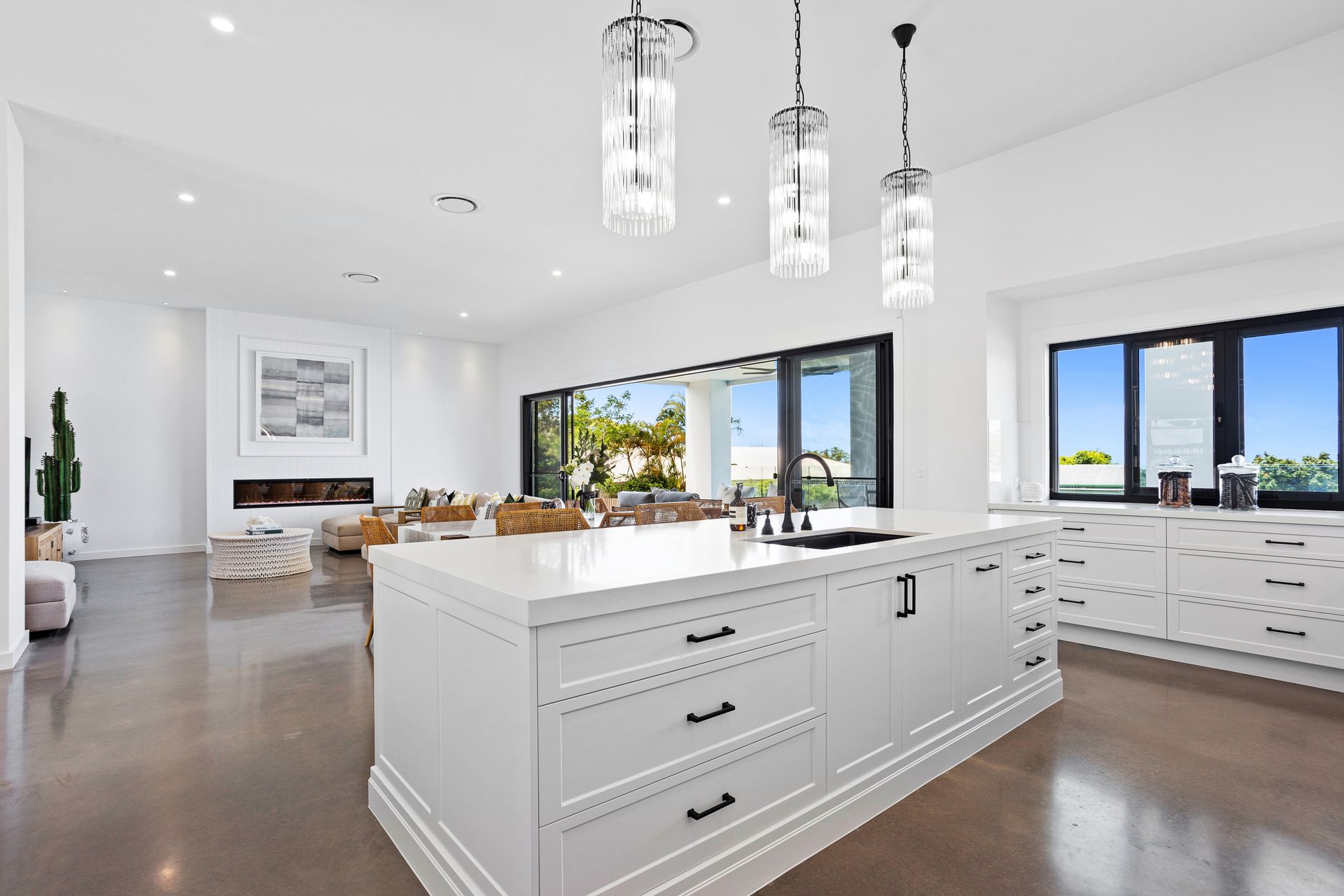 Spacious, modern kitchen with a white island, pendant lights, and sliding doors to an outdoor area.