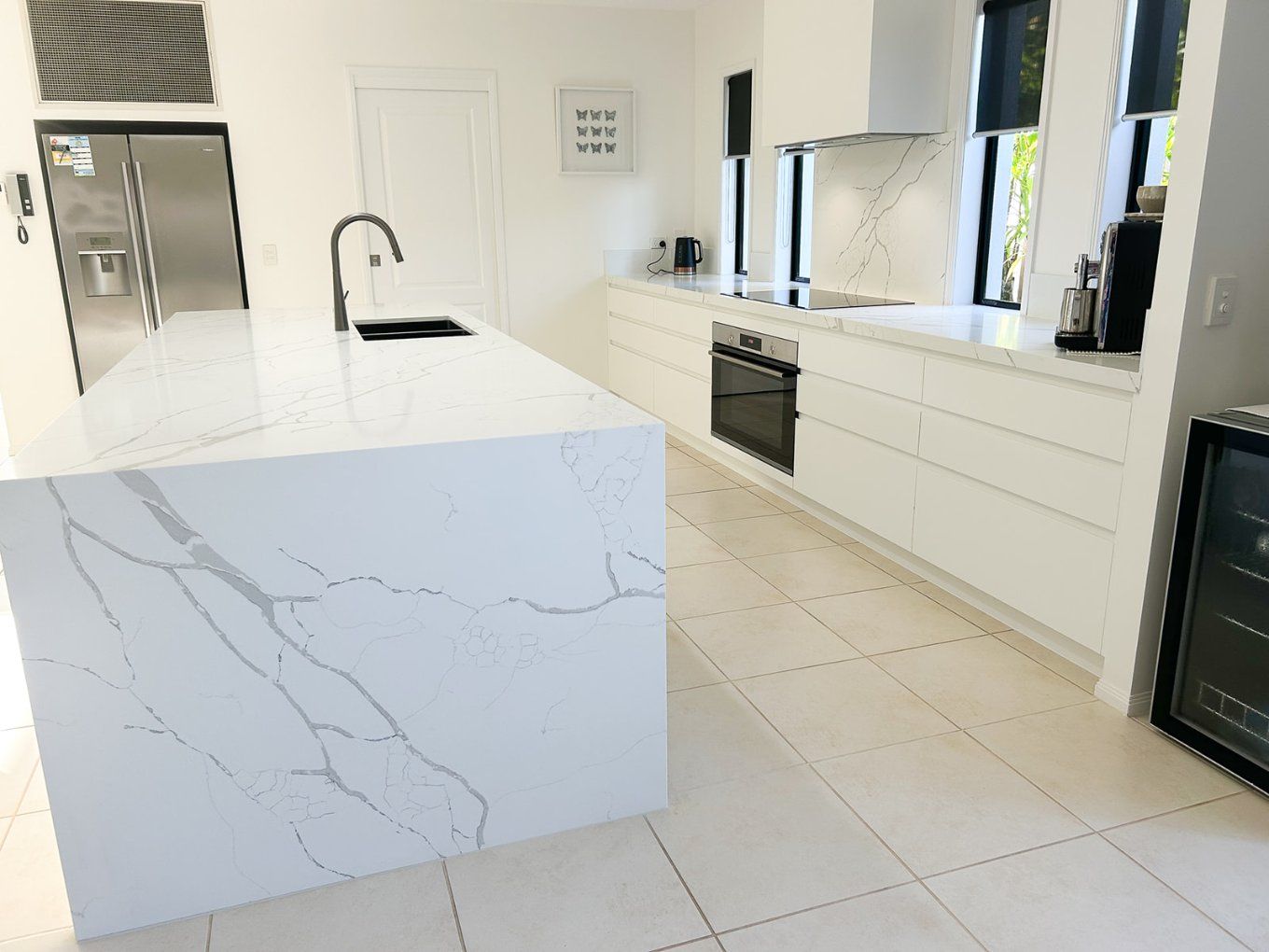 Bright, Modern Kitchen With a White Marble Island and Countertops, Black Faucet, and a Built-in Oven — Truline Cabinets In Tuchekoi, QLD