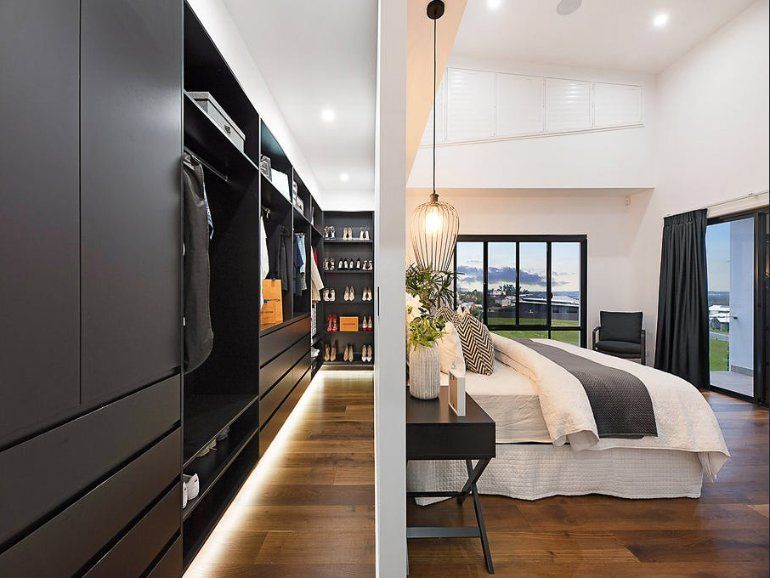 Walk-in Closet With Dark Cabinets, Open to a Bedroom With a Bed, Windows, and a View — Truline Cabinets In Tuchekoi, QLD