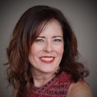 A woman with long brown hair and red lipstick is smiling for the camera.