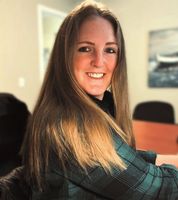 A woman is smiling while sitting in a chair in front of a computer.