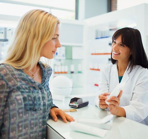 Pharmacist speaking with a customer at a bright pharmacy counter