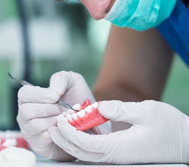 A dentist is working on a model of a person 's teeth.