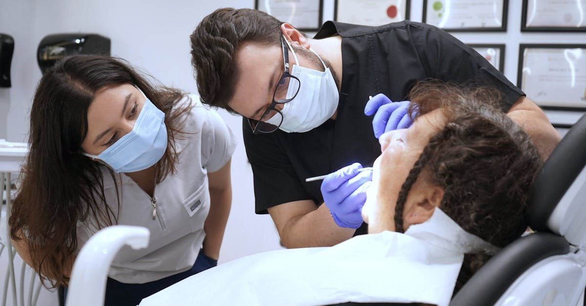 Two dentists are examining a patient 's teeth in a dental office.