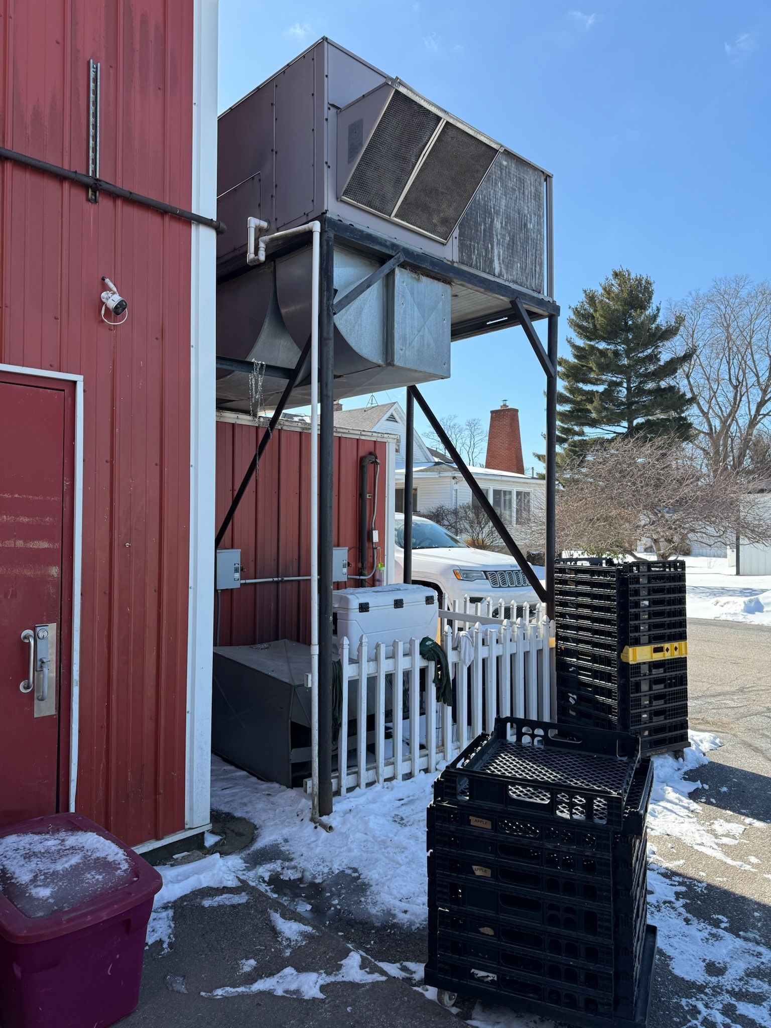 Red barn with a metal structure holding an HVAC unit. Snow on the ground.