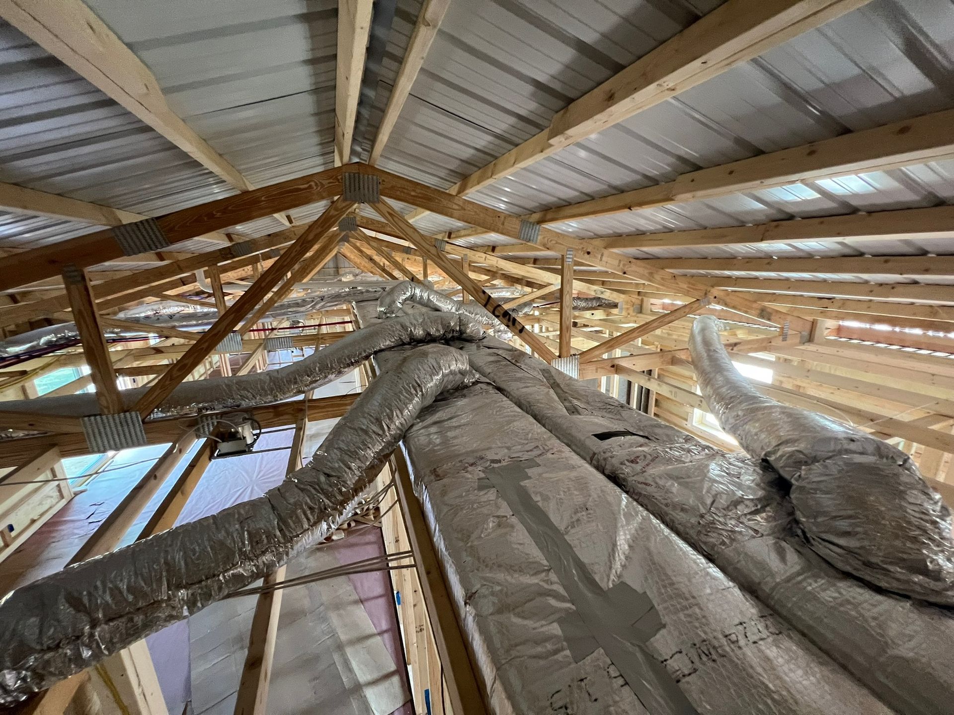 Wooden roof framing with insulated ductwork running through it.