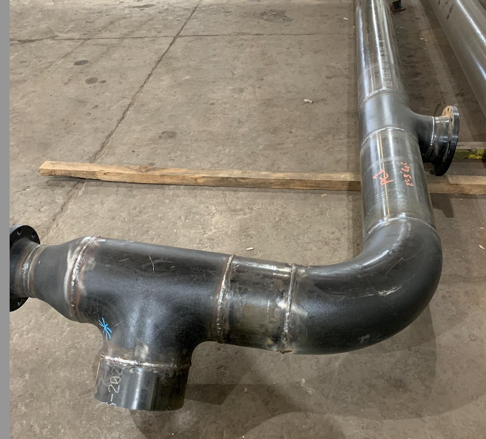Black metal pipe assembly on a gray surface, with welded joints and flange.