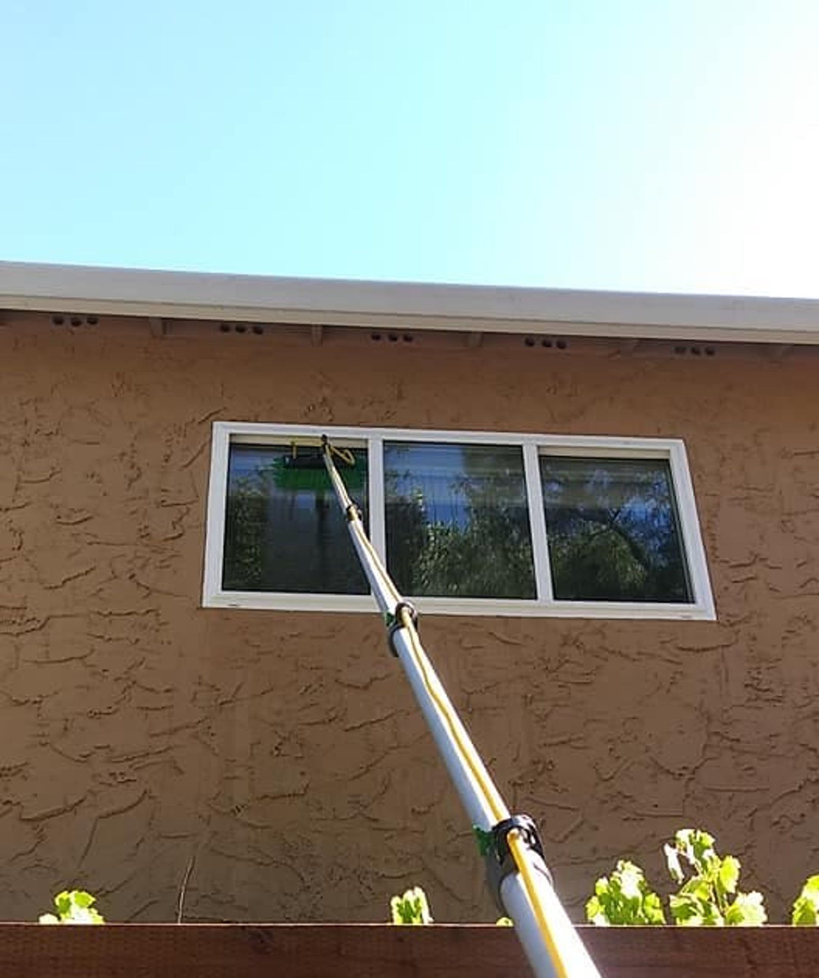 A person cleaning a window with a long pole.