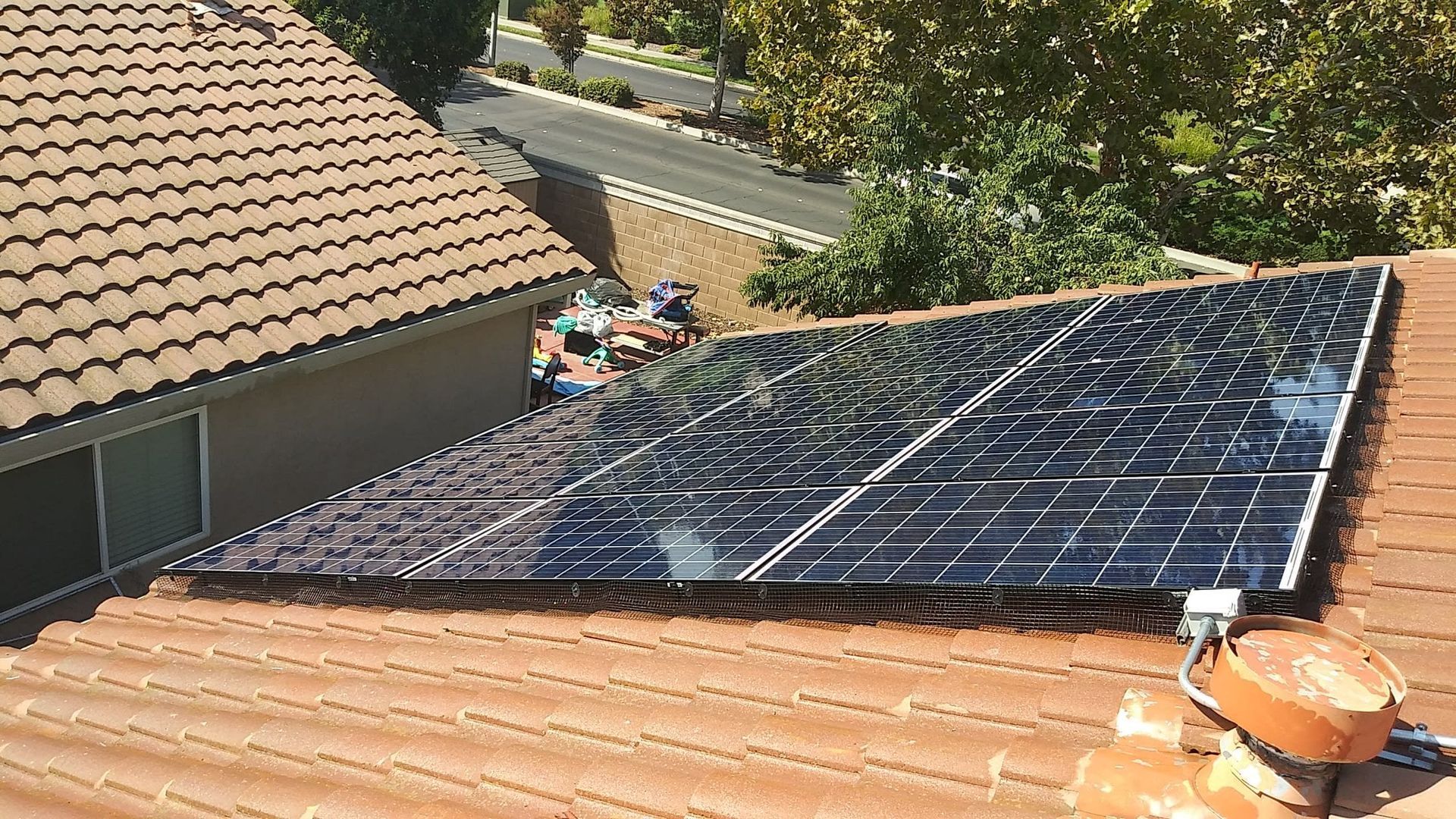 Solar panels on a terracotta tile roof, angled towards the sun.