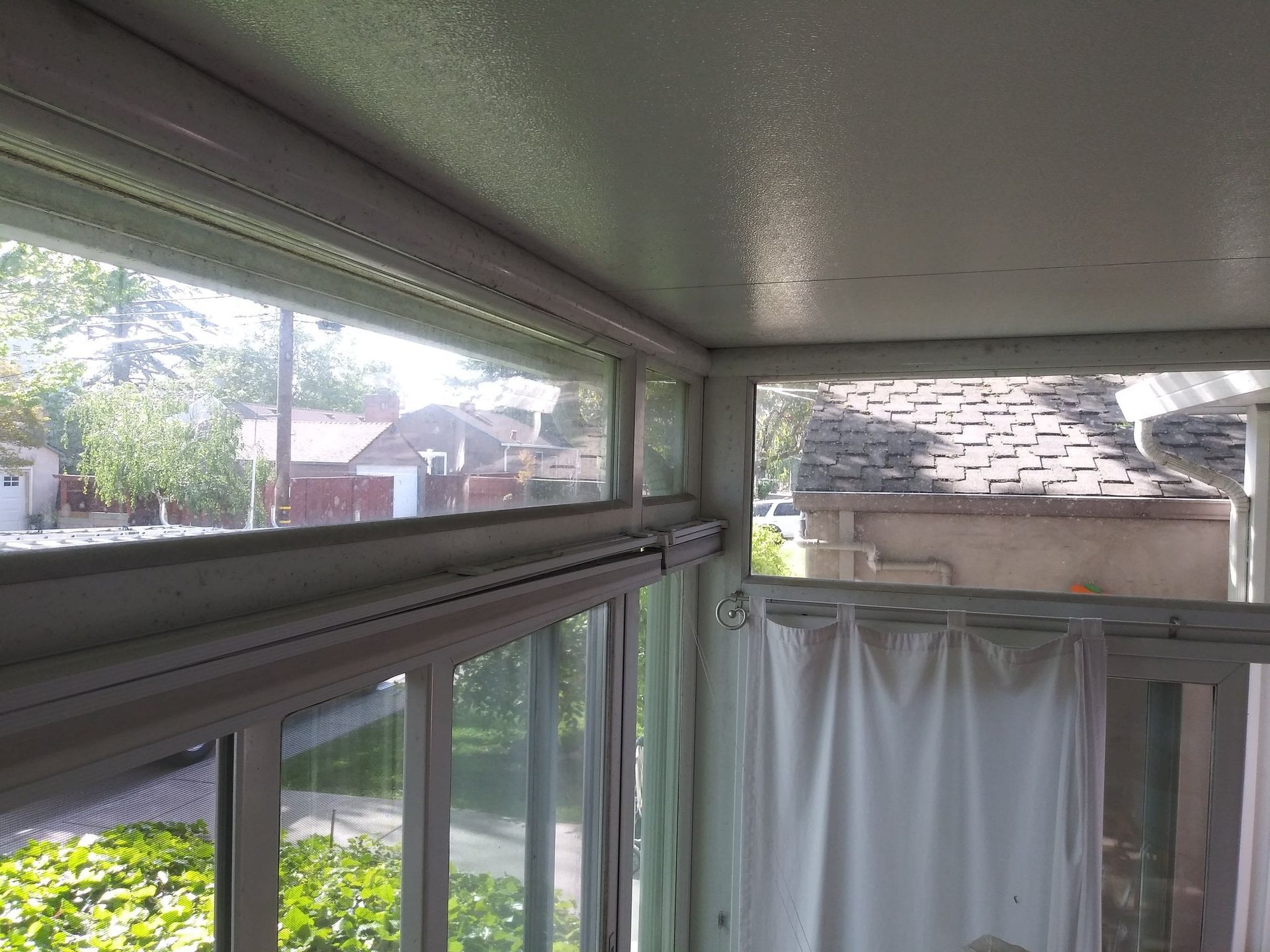 Corner room with windows, sunlight, neighborhood view, white trim and blinds.