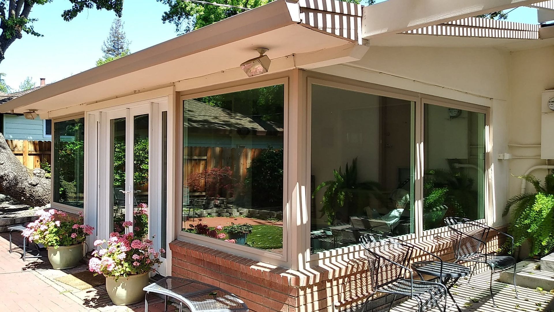 Building exterior with large windows, potted flowers, and outdoor seating.