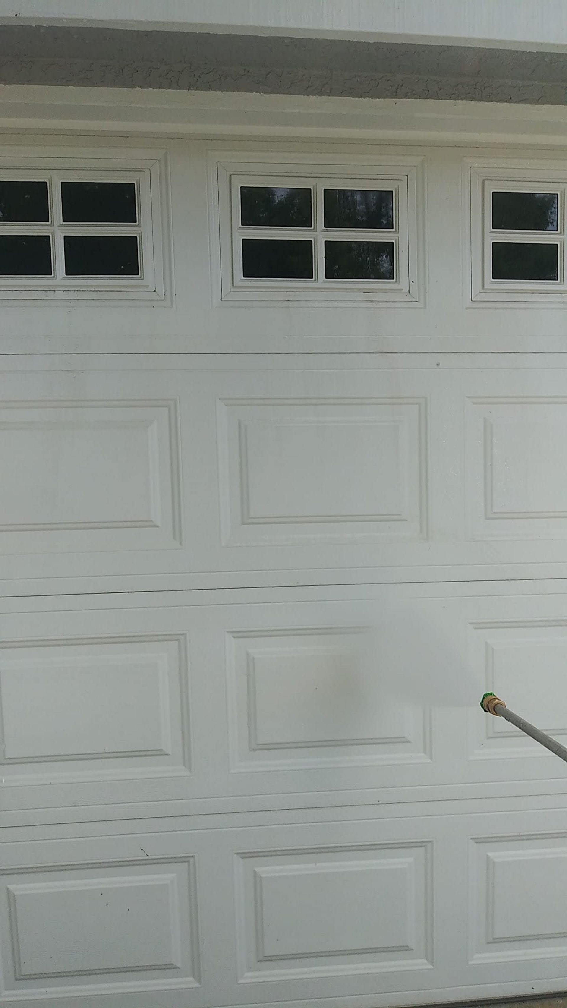 White garage door being pressure washed.