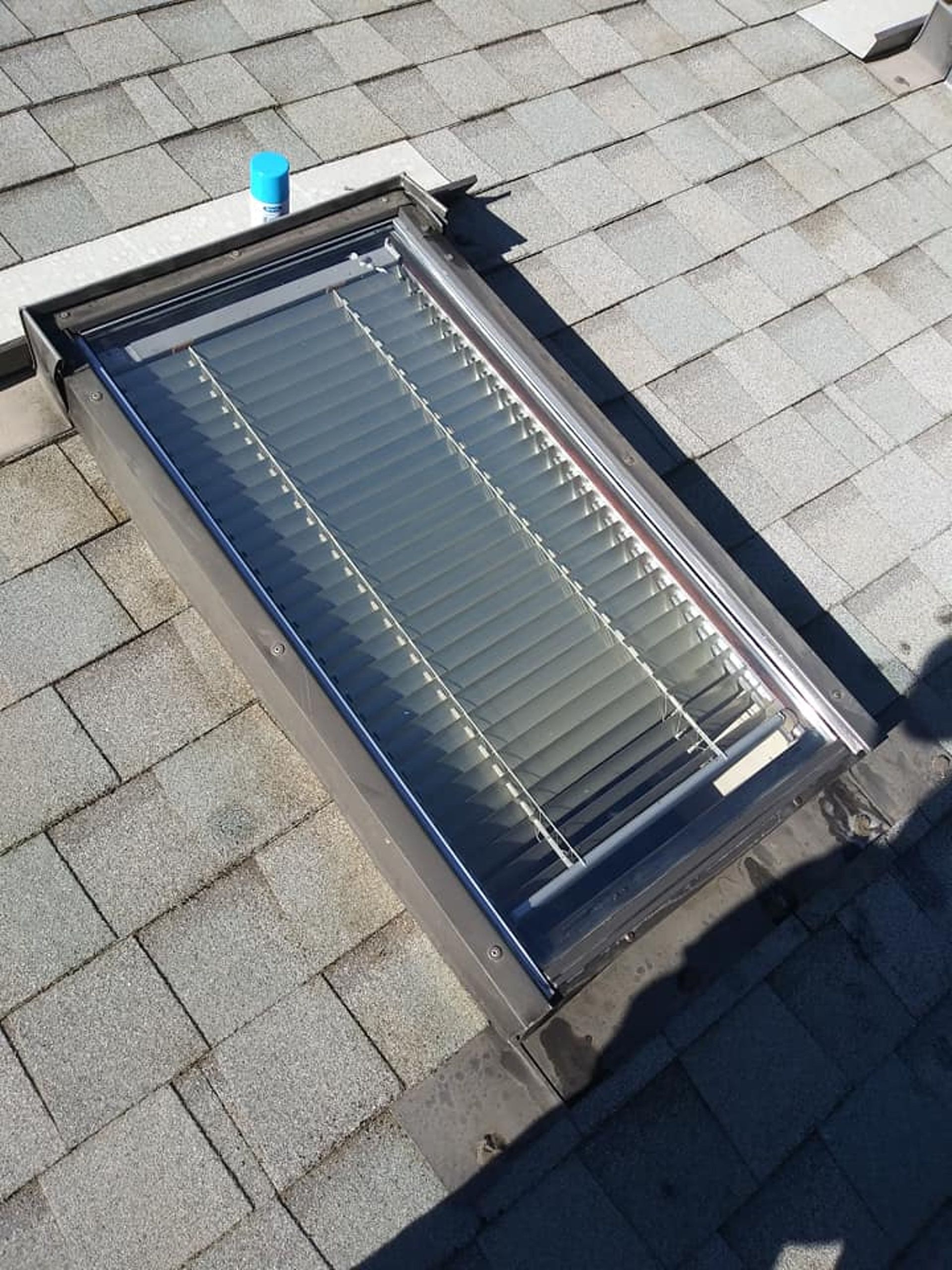 Skylight on a shingle roof with interior blinds.