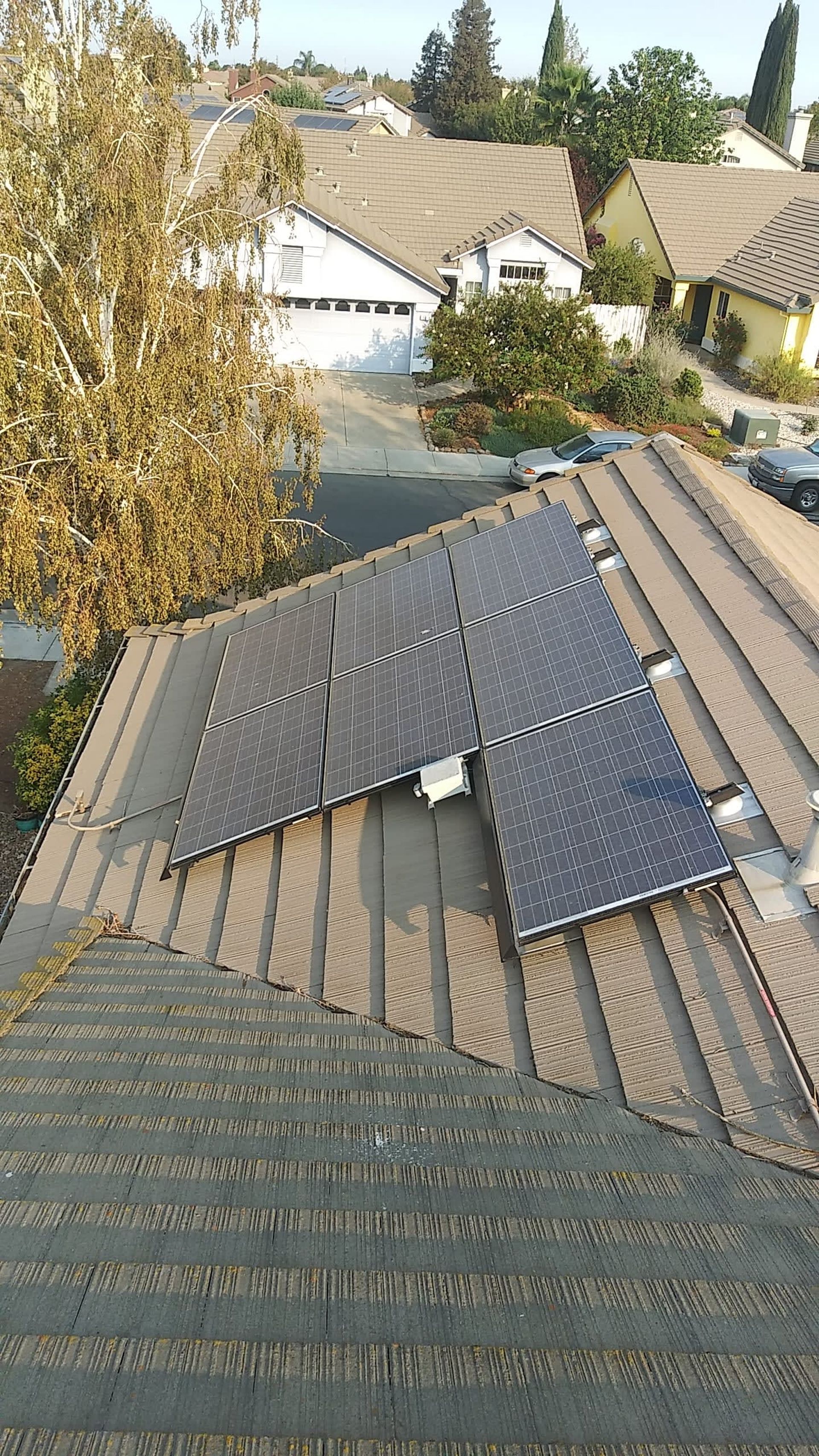 Solar panels on a residential roof, sunny day. Other houses in background.