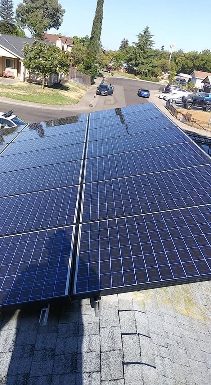 Solar panels installed on a roof, reflecting sunlight.