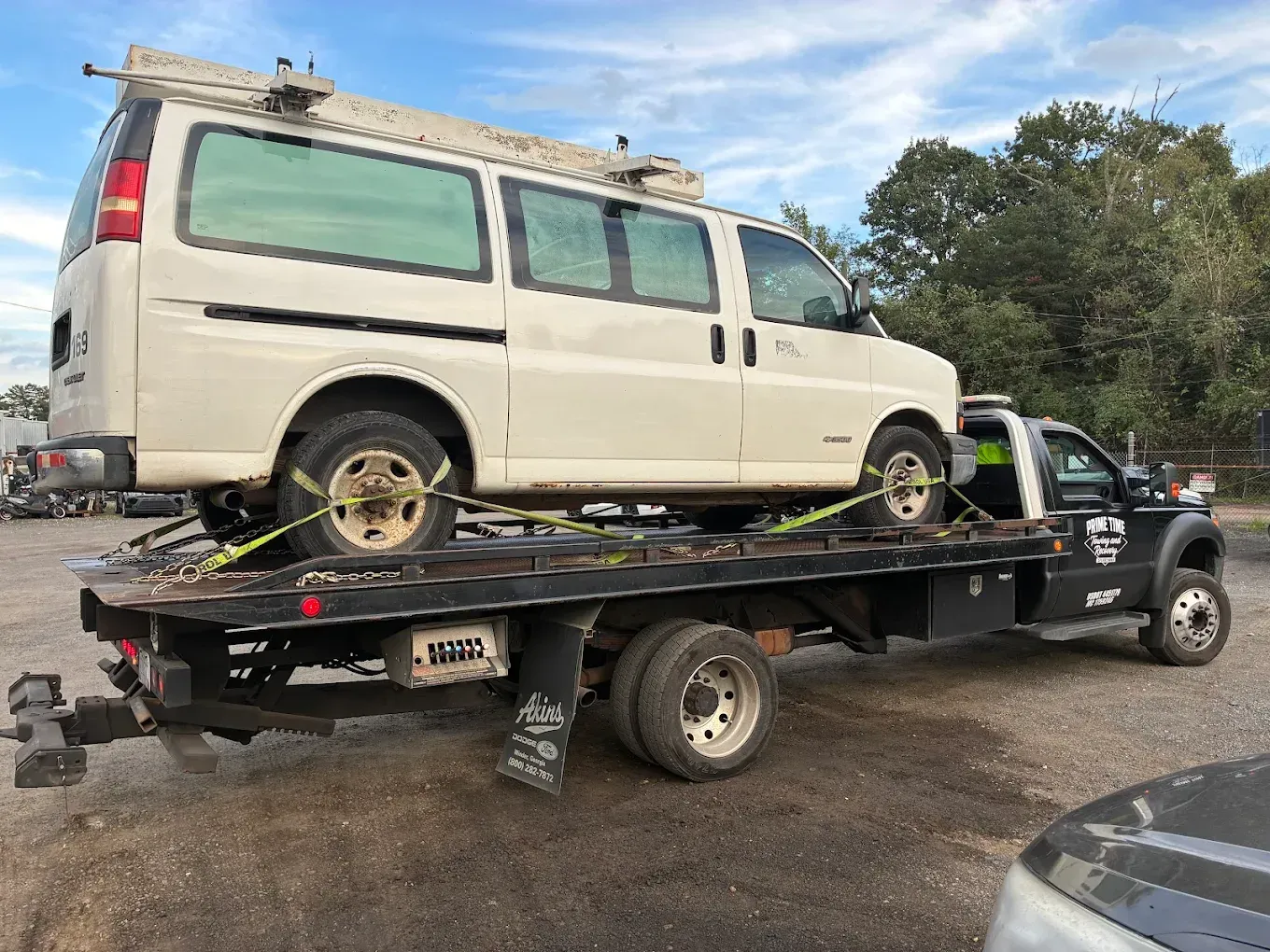 White van secured on a tow truck flatbed in a parking lot