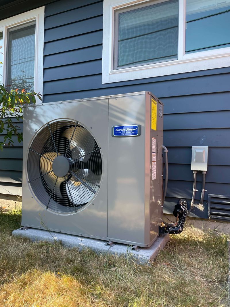 A large fan is sitting on the side of a house.
