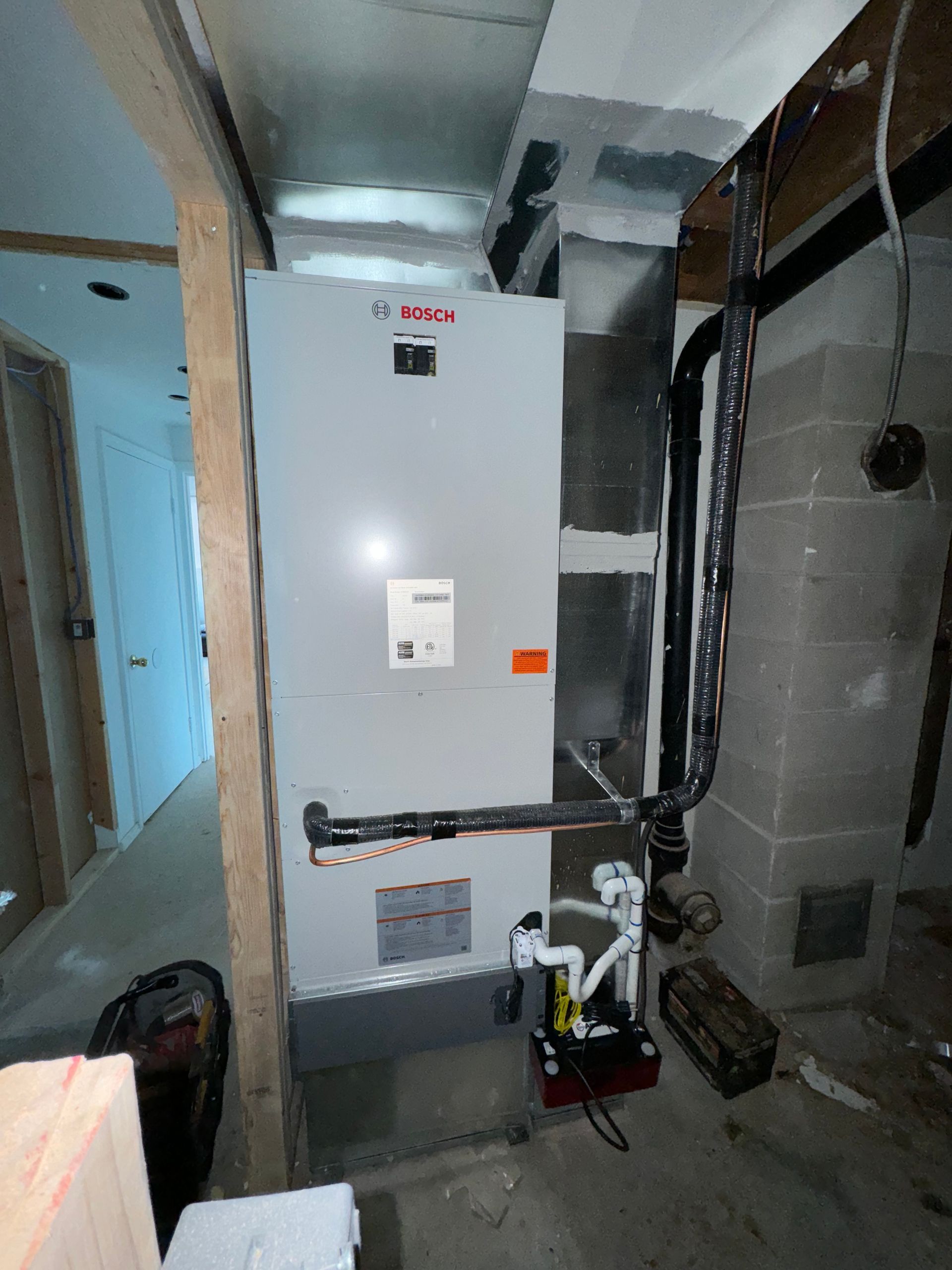 A white air conditioner is sitting in a corner of a room.