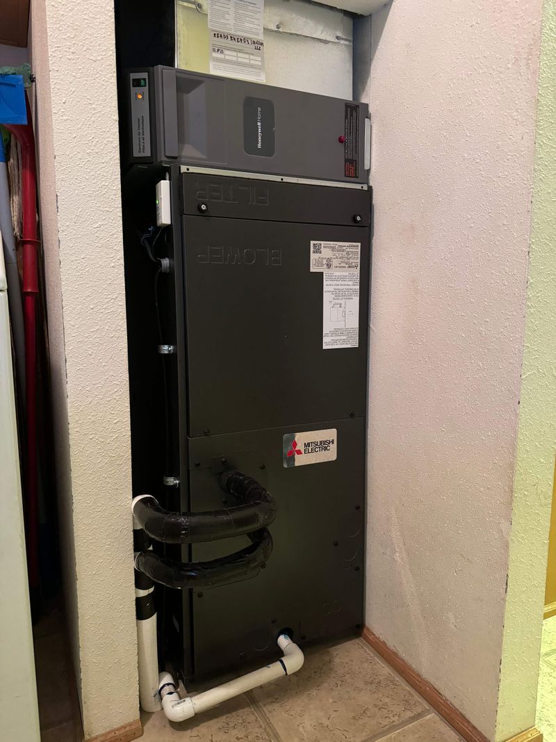 A black refrigerator is sitting in a corner of a room.