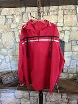 A red shirt is hanging on a hanger in front of a stone wall.