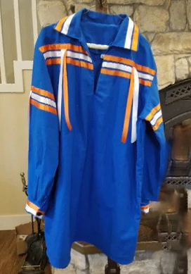 A blue shirt with orange and white stripes is hanging on a hanger in front of a fireplace.