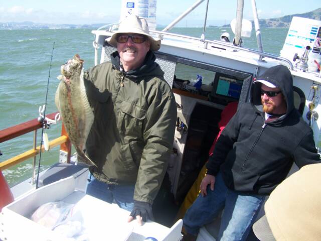 A man in a hat is holding a fish on a boat