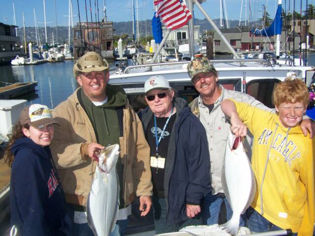 A group of people posing for a picture while holding fish