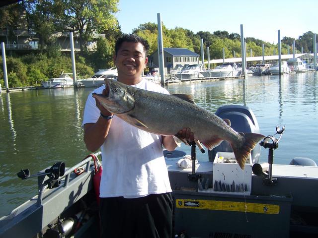 A man on a boat holding a large fish