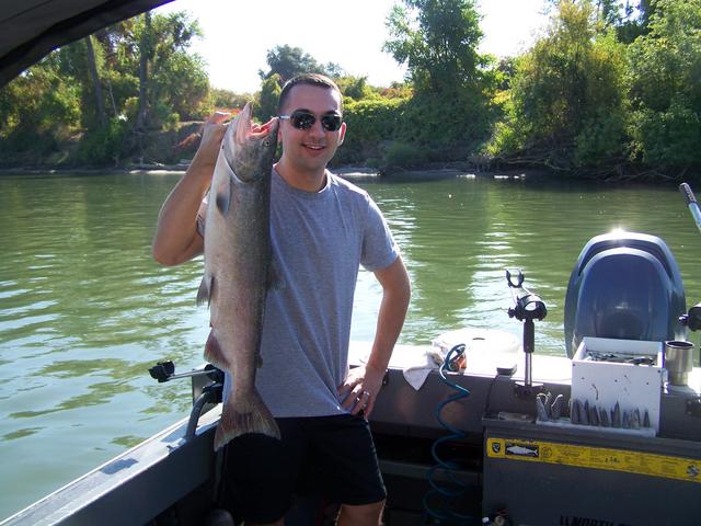 A man on a boat holding a large fish