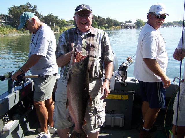 A man is holding a large fish on a boat