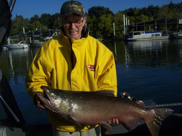 A man in a yellow jacket is holding a large fish