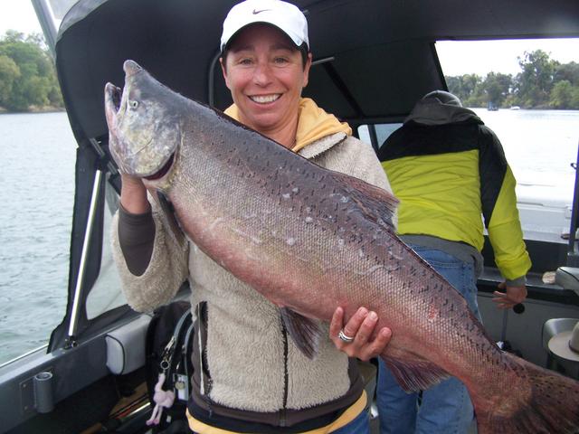 A woman is holding a large fish in front of a boat