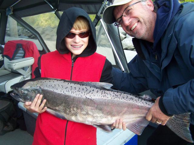 A man and a boy are holding a large fish