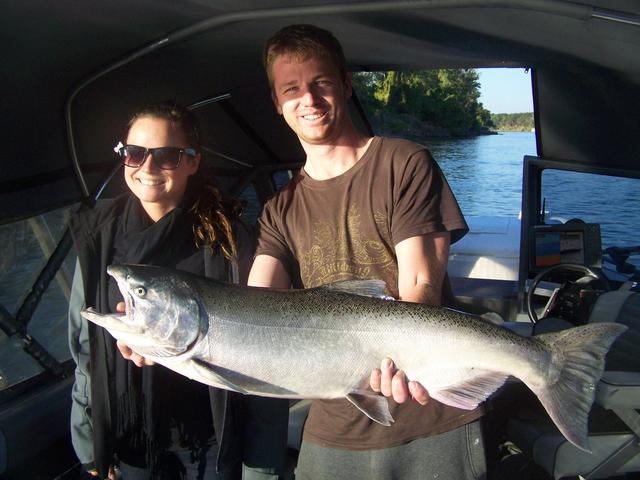 A man and a woman holding a large fish in a boat