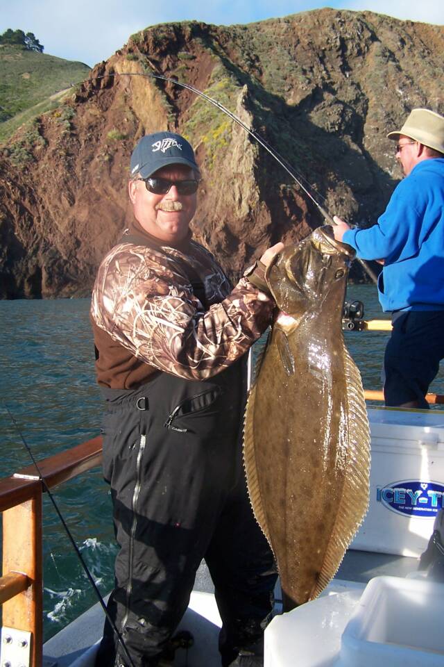 A man is holding a large fish on a boat