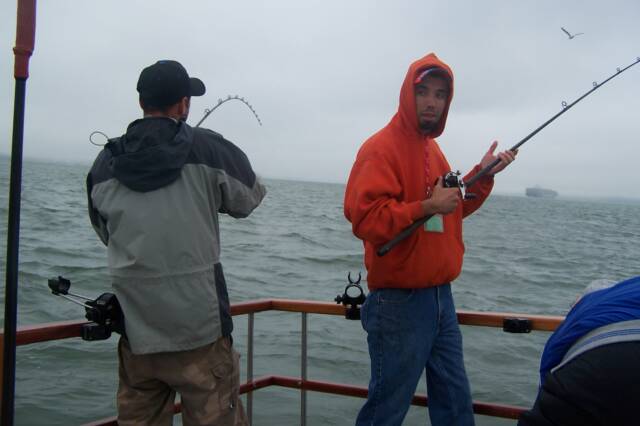Two men are fishing on a boat on a cloudy day